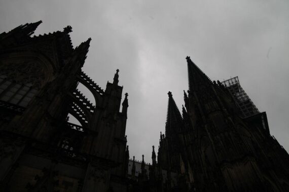 Kölner Dom unter grauen Wolken, Regen und trübem Himmel in Nordrhein-Westfalen.