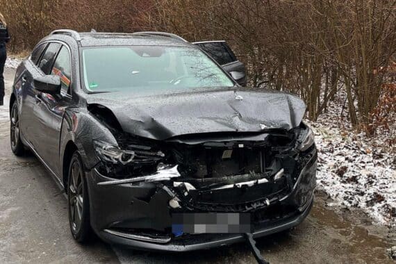 Zwei beschädigte Autos nach frontalem Unfall, Polizisten und Einsatzfahrzeuge sind zu sehen.