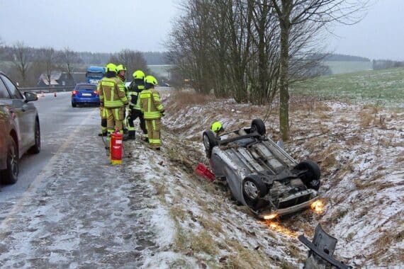 Ein kaputtes Auto im Straßengraben, Polizei und Rettungswagen sind vor Ort.