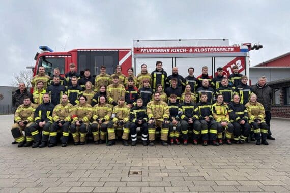 Feuerwehrmann in Uniform feiert erfolgreichen Abschluss der Grundausbildung mit neuen Mitgliedern.