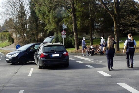 Unfallstelle mit zwei beschädigten Autos, Polizei vor Ort, Verletzter wird ins Krankenhaus gebracht.