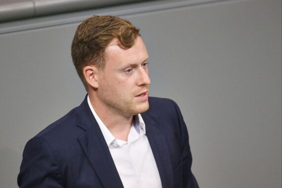 Ein Bild von Jan Wenzel Schmidt, umgeben von politischen Symbolen oder einer AfD-Fraktionssitzung.