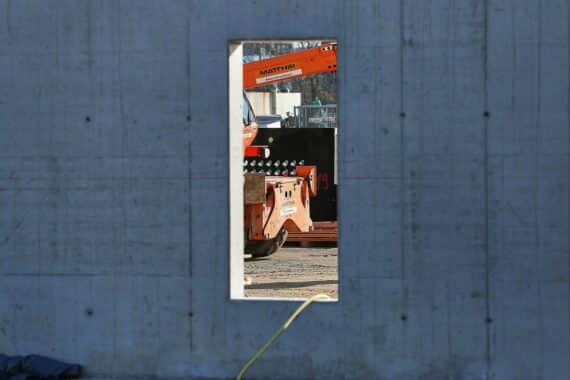 Baustelle mit Handwerkern, Baustellenfahrzeugen und Materialien, symbolisiert Umsatzsteigerung im Ausbaugewerbe.