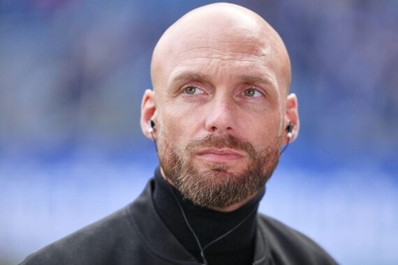 Nils-Ole Book, neuer Sportdirektor von Borussia Dortmund, posiert selbstbewusst in Fußballumgebung.