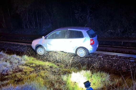 Verkehrsunfall in Alsdorf: schwer verletzte Frau, Polizei vor beschädigtem Auto auf Bahngleisen.