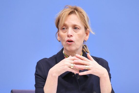 Bild von Karin Prien im Unterricht, umgeben von Schülern, die über den Iran-Krieg diskutieren.