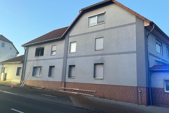 Brand in einem Mehrfamilienhaus mit Feuerwehr, Rauch und rettenden Einsatzkräften.