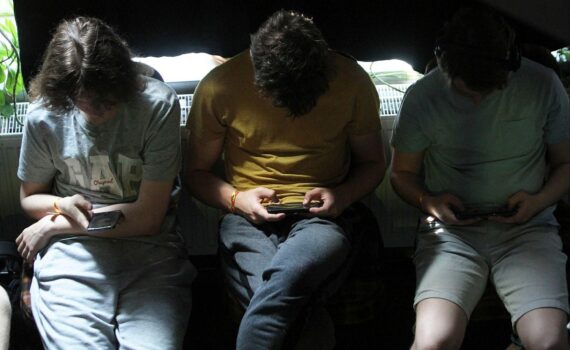 Junge Menschen nutzen Smartphones, symbolisiert Gefahren von sozialen Medien, Aufklärungskampagne der Regierung.