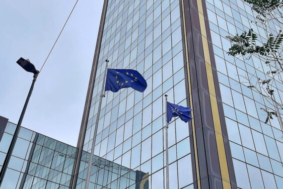 EU-Fahnen im Vordergrund, symbolisieren diplomatische Besorgnis über humanitäre Lage in Iran.