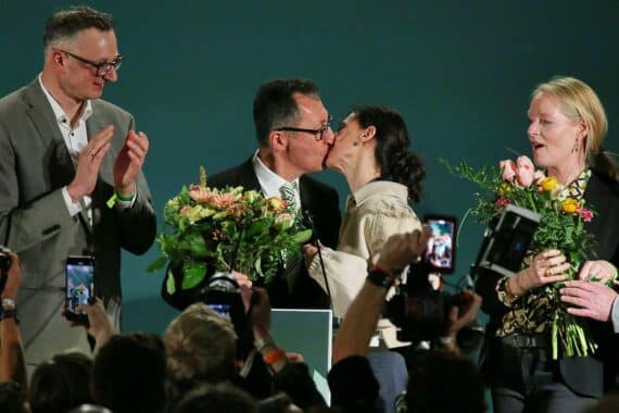 Cem Özdemir, lächelnd in Anzug, vor Wahlplakat, symbolisiert die Grünen nach Landtagswahl.