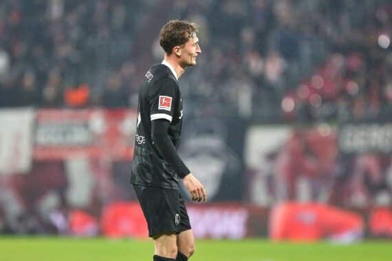 Fußballspiel, jubelnde Fans, spannende Szenen, Spielstand 0:1, Teamlogos SC Freiburg und KRC Genk.