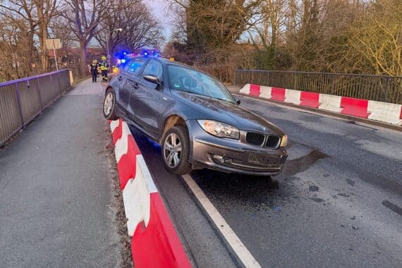 Unfallstelle mit Pkw gegen Leitwand, Feuerwehr im Einsatz, ausgelaufene Kühlflüssigkeit, gesperrte Straße.