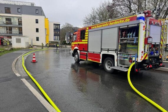 Feuerwehrwagen vor einem evakuierten Gebäude, Einsatzkräfte überprüfen Gasgeräusche und Rauchentwicklung.