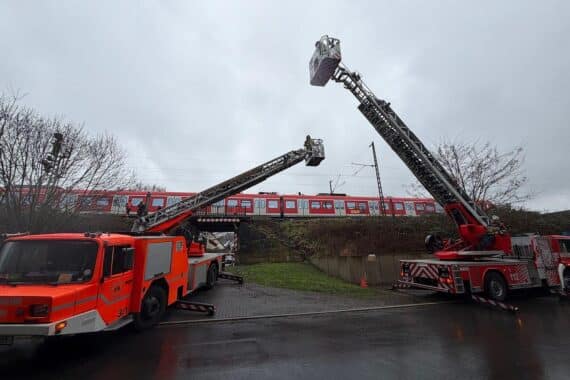 Feuerwehr evakuiert Fahrgäste aus S-Bahn mit Drehleitern, sicherer Transport auf Boden.