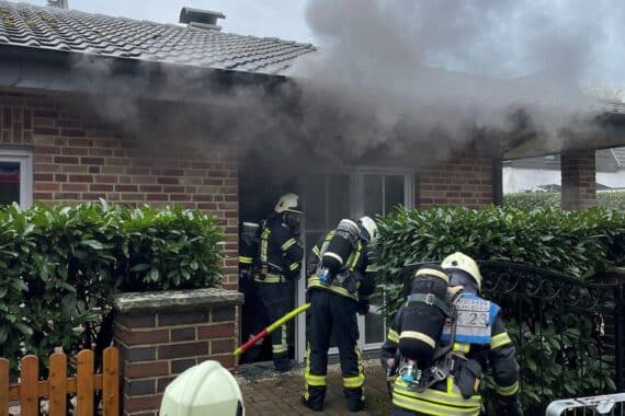 Feuerwehr löscht Brand im Dachstuhl eines Wohnhauses in Dinslaken. Rauch und Einsatzkräfte sichtbar.