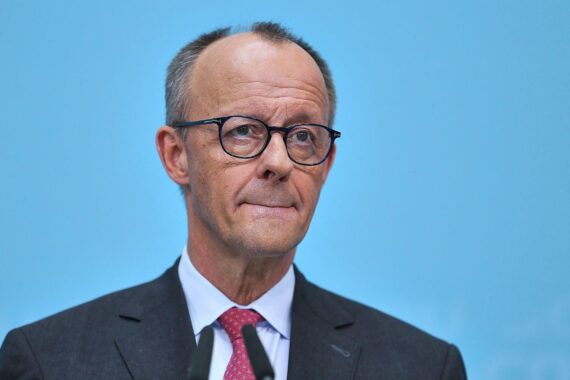 Friedrich Merz spricht bei einer politischen Veranstaltung in Berlin, im Hintergrund Wahlgrafiken.