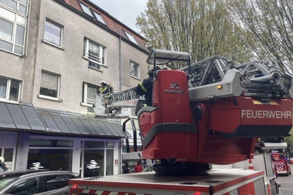 Frau wird nach Wohnungsbrand von Feuerwehr und Rettungsdienst betreut, Einsatzkräfte arbeiten.