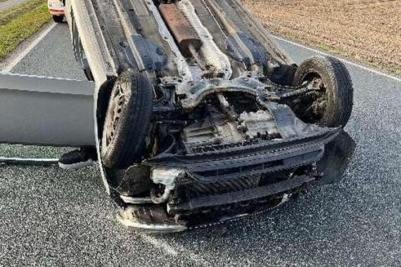 Ein umgedrehtes Auto auf der Straße, Feuerwehr und Polizei bei der Unfallaufnahme.