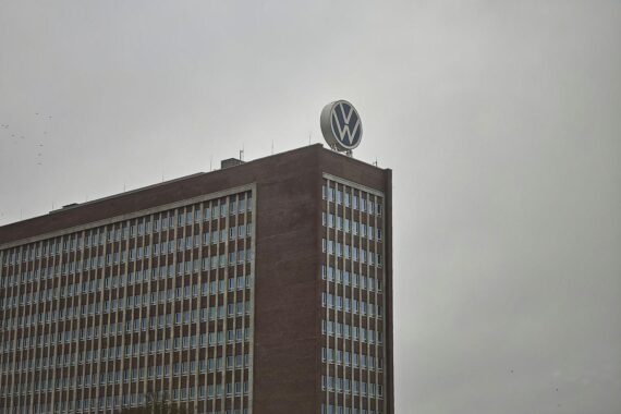 Volkswagen-Logo, Arbeiter in Werkhallen, symbolische Darstellung von Boni und Krisenmanagement.