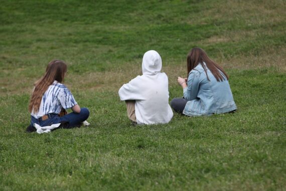 Drei junge Frauen im Park, symbolisieren respektvollen Umgang und Geschlechterdiskussion in Deutschland.