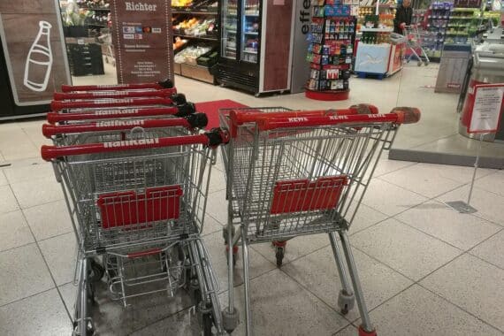 Einkaufswagen vor einem Supermarkt, Symbol für Mehrwertsteuer und wirtschaftliche Diskussionen in Deutschland.