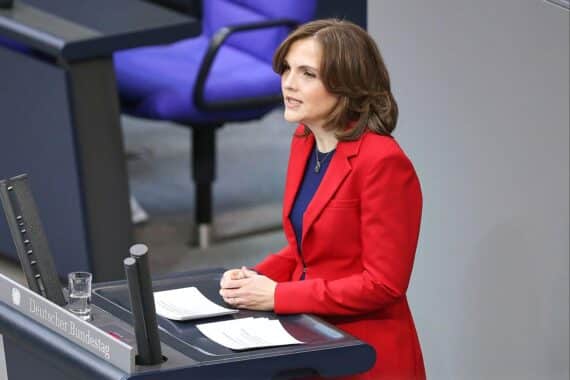 Elisabeth Kaiser kritisiert den Baustopp der Nationalbibliothek Leipzig, symbolisiert durch Bücher und Kultur.