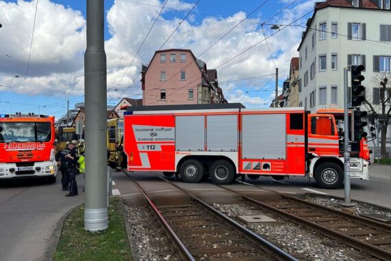 Einsatzkräfte befreien verletzte Person unter Straßenbahn, betreuen Fahrgäste und Passanten.