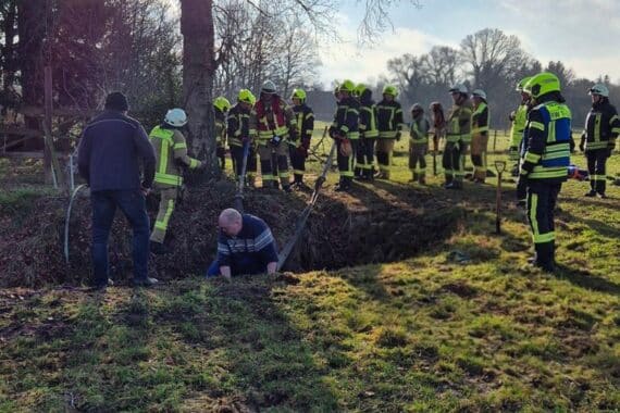 Pony wird von Feuerwehr aus Graben gerettet, umringt von Einsatzkräften und Tierarzt.