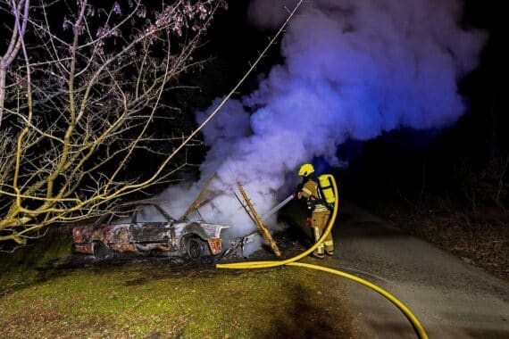Feuerwehr löscht brennenden Pkw in Nacht, Feuerwehrleute mit Wärmebildkamera, Polizei ermittelt.