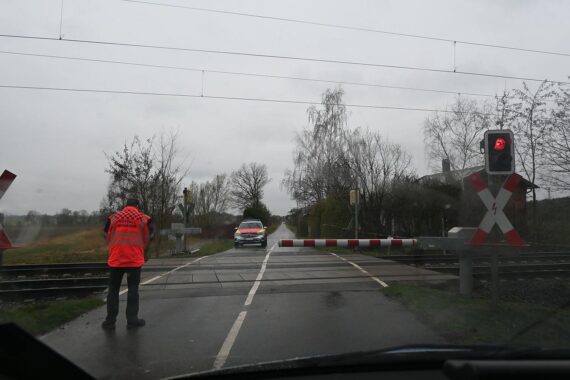 Beschädigte Bahnschranke am Unfallort, Polizei ermittelt nach Fahrerflucht.