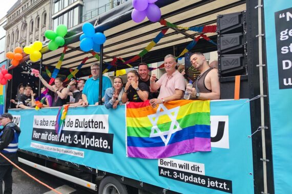 Bunte Parade mit LGBTQ+-Flaggen, Menschenfeier und Regierungswagen beim Christopher-Street-Day in Berlin.