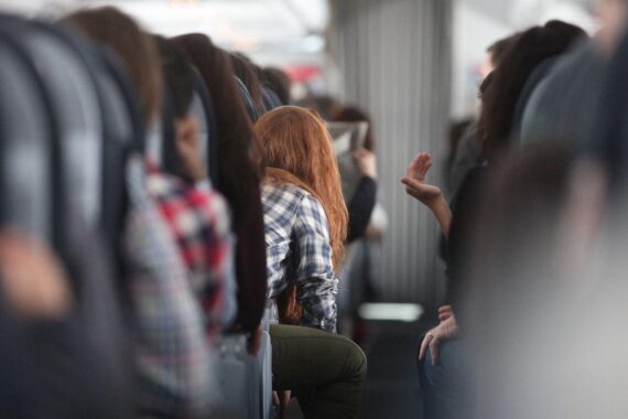 Rothaarige Frau im Flugzeug, Symbol für Reisekomfort und anstehenden Steueränderungen im Luftverkehr.