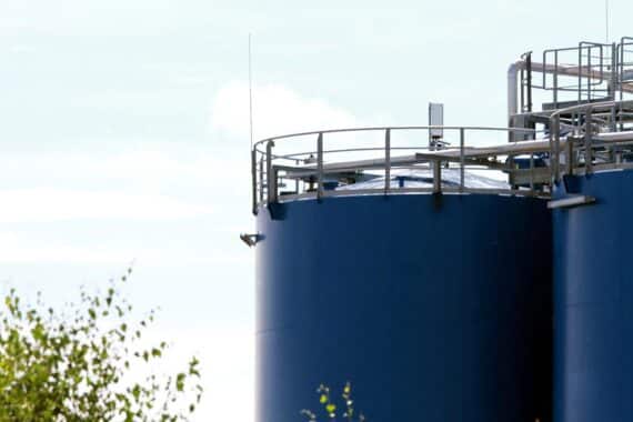 Öltanks mit Preisschildern, die steigende Preise für Öl und Gas symbolisieren.