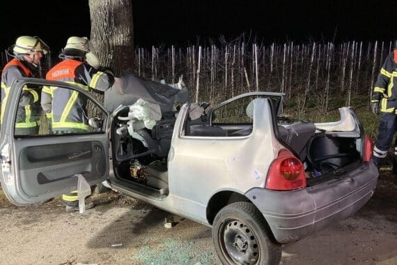 Ein schwer beschädigtes Auto nach einem Unfall, Feuerwehrleute bei der Rettung des Fahrers.