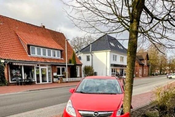 Ein Opel Corsa nach einem Unfall, umgeben von Schäden an Fassade und geparktem Auto.