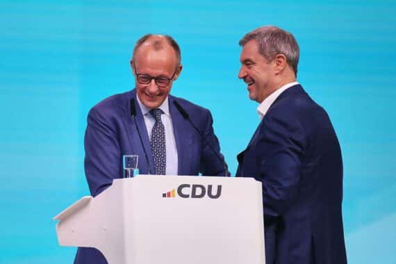 Friedrich Merz und Markus Söder lächeln freundschaftlich, symbolisieren Zusammenarbeit und politische Unterstützung in Deutschland.