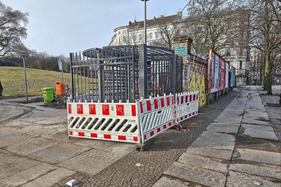 Zaun des Görlitzer Parks mit beschädigten Toren und Fahrrädern im Hintergrund.