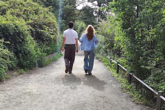 Mann und Frau spazieren in der sonnigen Landschaft Baden-Württembergs unter Quellwolken.