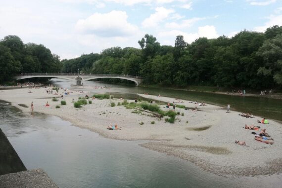 Sonniger Isarstrand in München mit lockeren Wolken und milden Temperaturen, ideal für Aktivitäten.