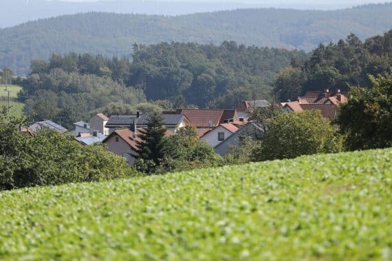 Sonniger Himmel über einem bayerischen Dorf mit wenigen Wolken und Häusern.