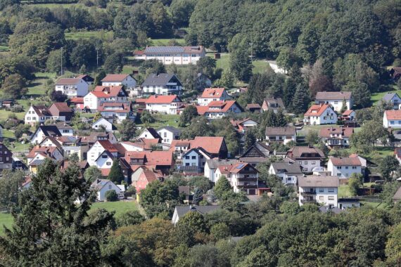 Helle Wohnhäuser unter sonnigem Himmel, symbolisierend das ruhige Hochdruckwetter in Hessen.