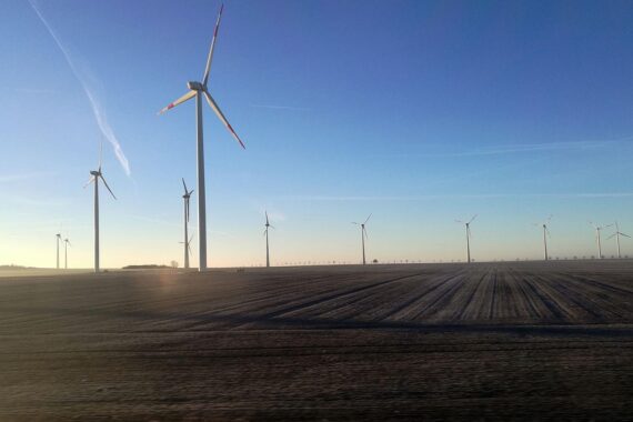 Sonnige Landschaft mit Windrädern, symbolisiert nachhaltige Energie an einem milden Frühlingstag.