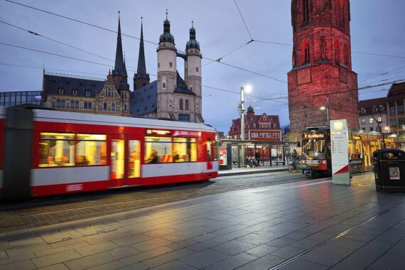 Straßenbahn auf belebtem Marktplatz in Halle (Saale), unter wechselhaftem Wetter mit Wolken.