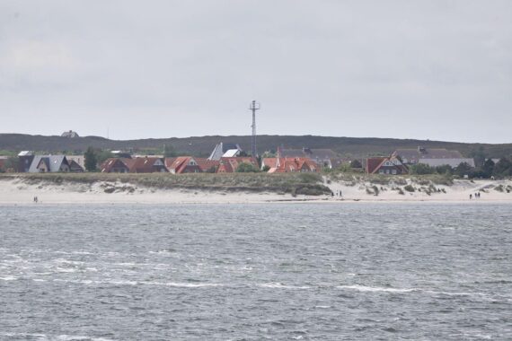 Heiterer Strand mit sanften Wellen, Wolken am Himmel, symbolisiert mildes Wetter in Schleswig-Holstein.