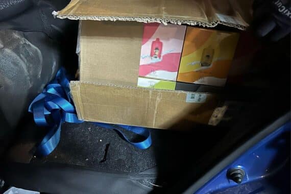 Zollbeamte beschlagnahmen über 1.000 unversteuerte E-Zigaretten in Fahrzeug vor Kiosk.