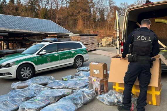 Zollbeamte kontrollieren Transporter mit geschmuggelten Motorradzubehör und Fahrrädern an Grenzübergang.