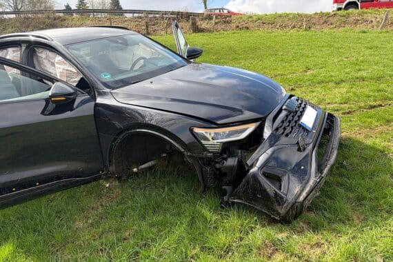 Verkehrsunfall mit Feuerwehr, Rettungswagen und Hubschrauber; leicht verletzte Personen auf Wiese.