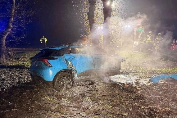 Tödlicher Verkehrsunfall: zerstörtes Auto, Baum, Feuerwehr im Einsatz, nächtliche Szene auf Straße.