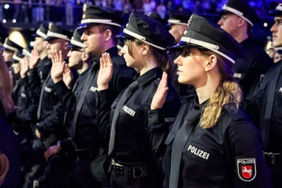 Polizeikommissaranwärter leisten feierlich ihren Diensteid, umgeben von Angehörigen und Gästen.