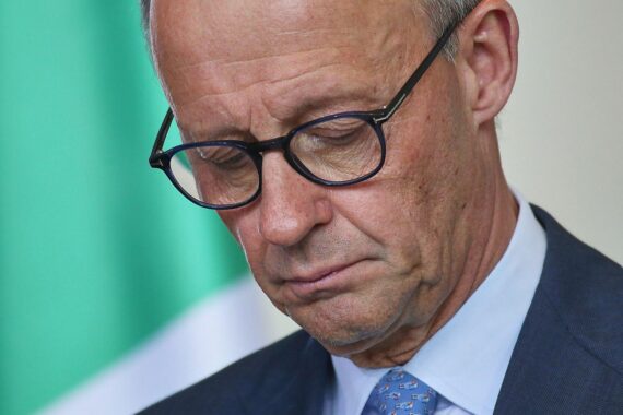 Friedrich Merz spricht vor Journalisten, während um ihn herum politische Unruhe herrscht.